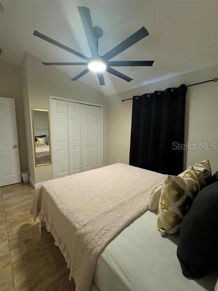 bedroom with lofted ceiling, ceiling fan, and a closet