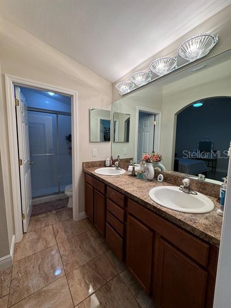 bathroom featuring vanity, vaulted ceiling, a shower with shower door, and toilet