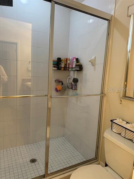 bathroom featuring a shower with door and toilet