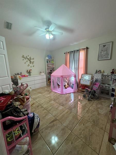 recreation room with tile patterned floors and ceiling fan