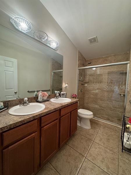 bathroom featuring vanity, toilet, tile patterned floors, and a shower with shower door