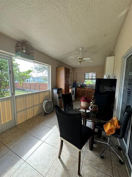 dining space featuring ceiling fan, lofted ceiling, a textured ceiling, and light tile patterned floors