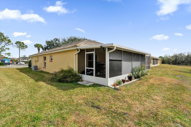 view of side of home with a lawn, a sunroom, and central air condition unit