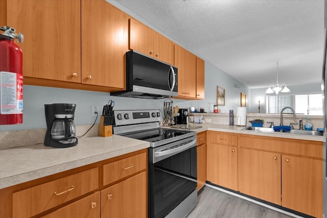 kitchen with sink, stainless steel range with electric cooktop, decorative light fixtures, a textured ceiling, and light hardwood / wood-style floors