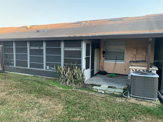 rear view of property featuring a yard, central AC, and a sunroom