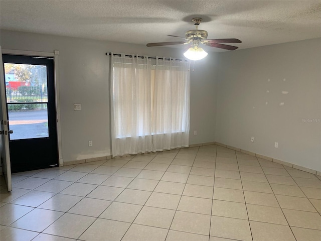 tiled empty room featuring ceiling fan and a textured ceiling