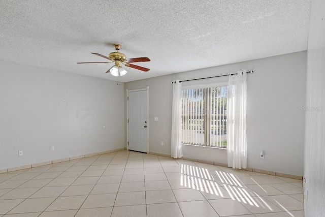 tiled spare room featuring baseboards, a textured ceiling, and a ceiling fan