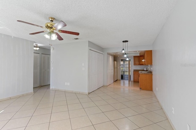 unfurnished living room with light tile patterned flooring, visible vents, a textured ceiling, and a sink