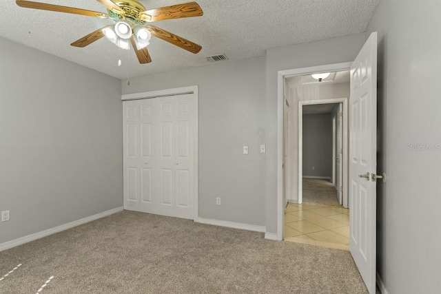 unfurnished bedroom featuring a textured ceiling, visible vents, a closet, and light carpet