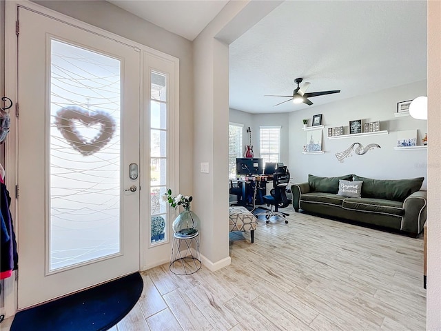 entrance foyer featuring a textured ceiling, ceiling fan, and light wood-type flooring