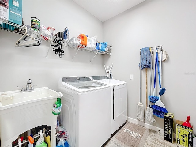 clothes washing area featuring sink, washing machine and clothes dryer, and light wood-type flooring