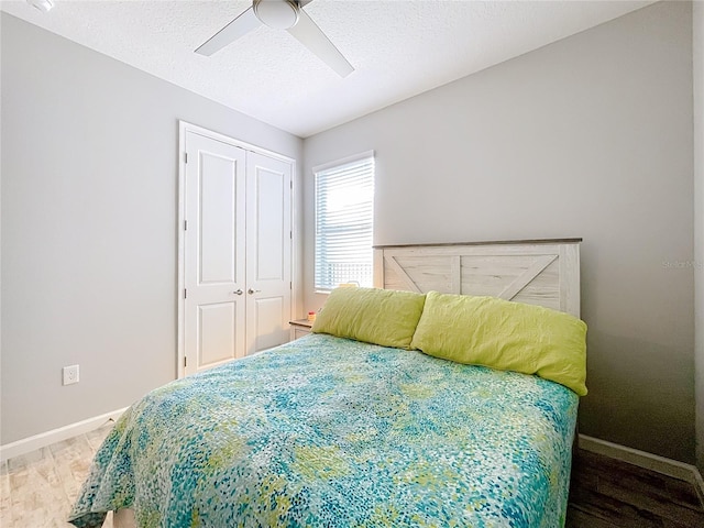 bedroom featuring hardwood / wood-style flooring, a closet, ceiling fan, and a textured ceiling