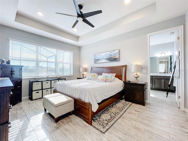 bedroom featuring a tray ceiling, light hardwood / wood-style flooring, and ceiling fan