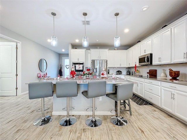 kitchen featuring appliances with stainless steel finishes, a center island, pendant lighting, and white cabinets