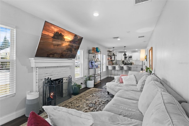 living room with dark hardwood / wood-style flooring, a fireplace, and plenty of natural light