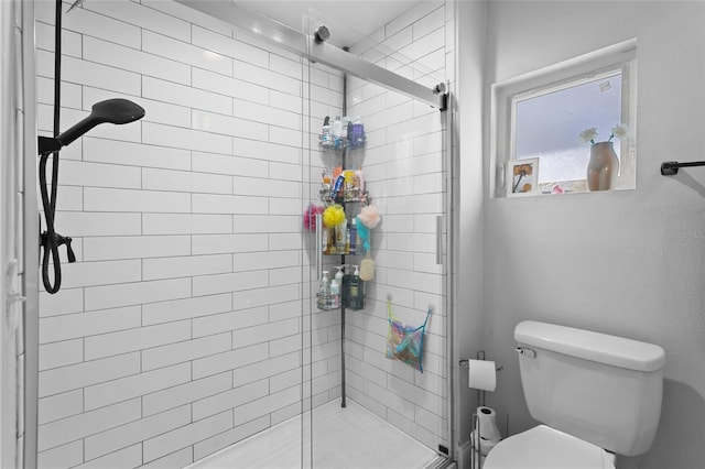 bathroom featuring toilet and a shower with shower door