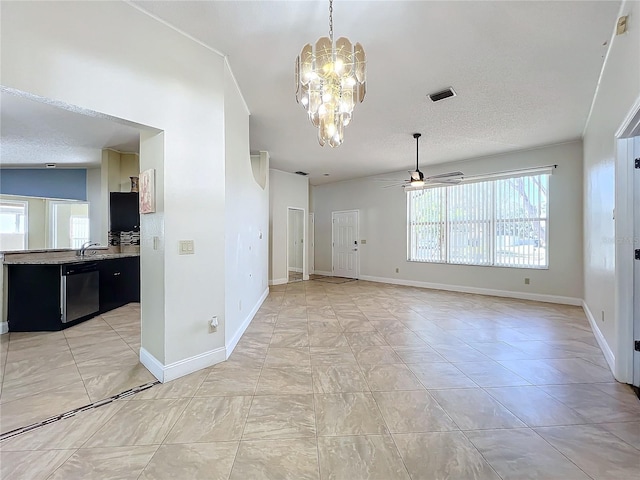 empty room featuring ceiling fan with notable chandelier, sink, and a textured ceiling