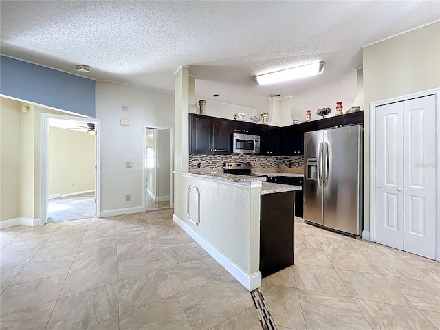 kitchen featuring light stone counters, stainless steel appliances, decorative backsplash, and a textured ceiling