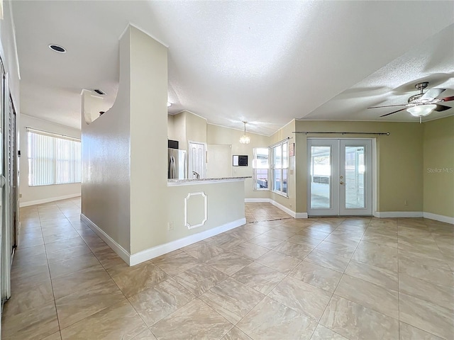 interior space featuring vaulted ceiling, a healthy amount of sunlight, a textured ceiling, and french doors