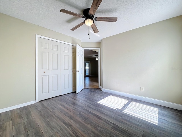 unfurnished bedroom featuring ceiling fan, dark wood-type flooring, a closet, and a textured ceiling