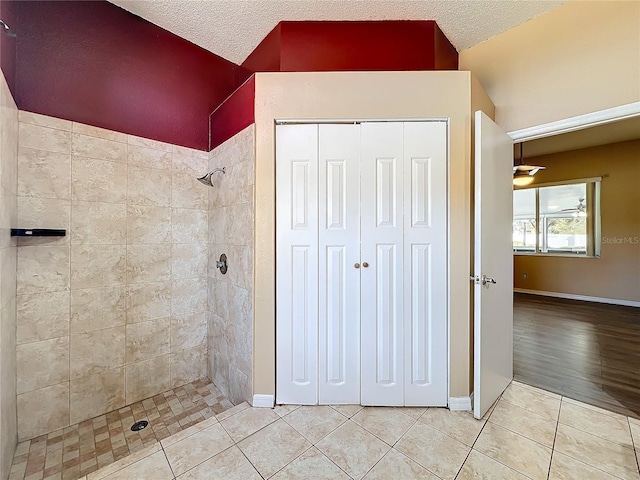 bathroom with tile patterned flooring, a tile shower, and a textured ceiling