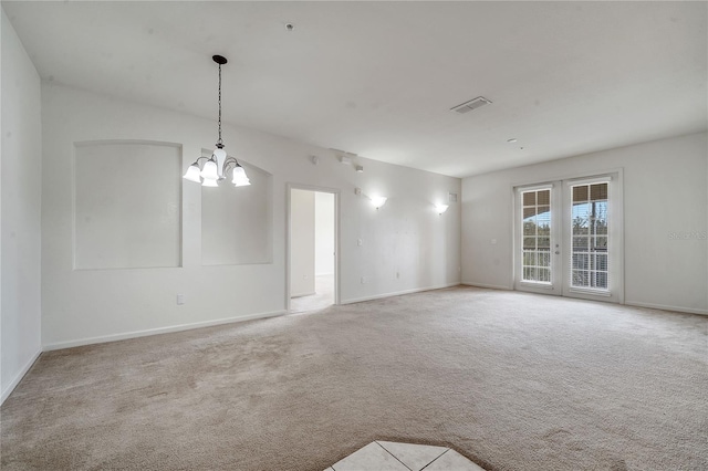 carpeted empty room with a chandelier and french doors