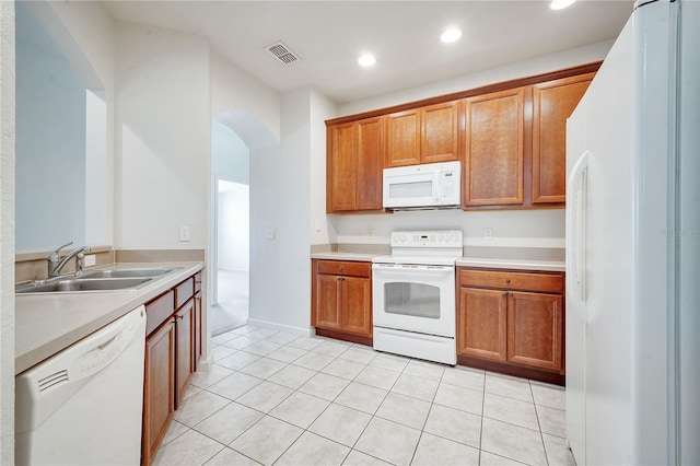 kitchen featuring sink, light tile patterned floors, and white appliances