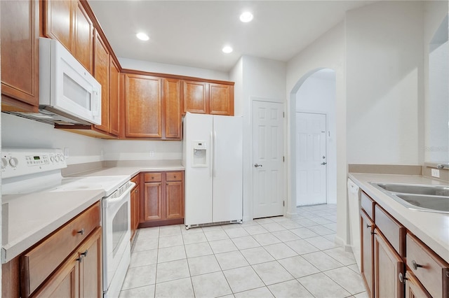 kitchen featuring sink, white appliances, and light tile patterned flooring