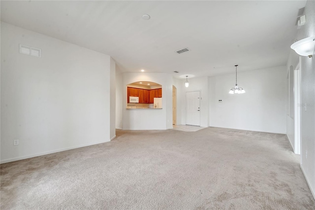 unfurnished living room featuring light colored carpet and a notable chandelier