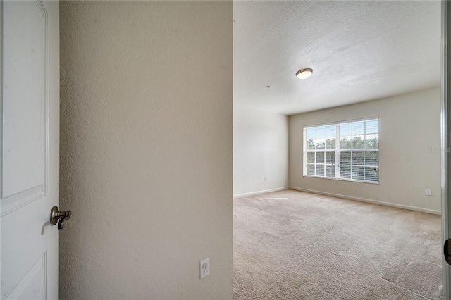 unfurnished room featuring light carpet and a textured ceiling