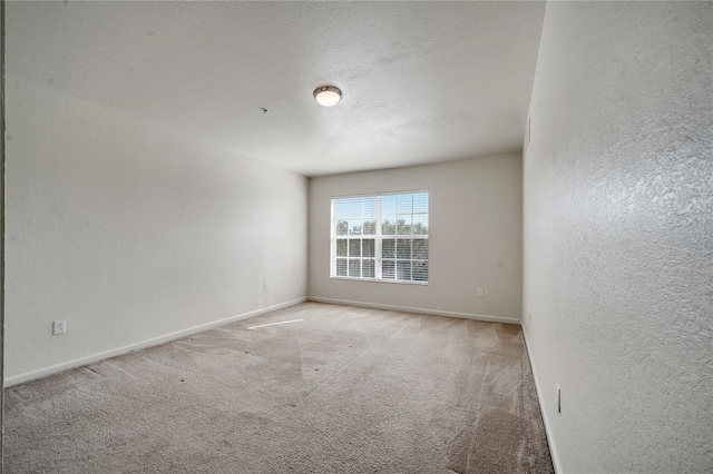 unfurnished room with light colored carpet and a textured ceiling