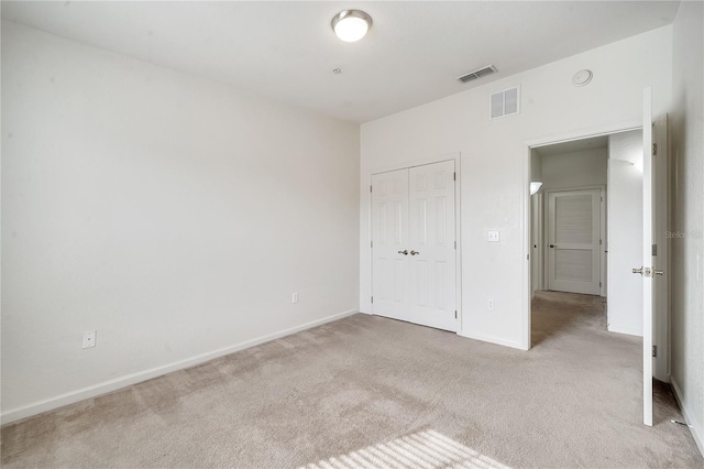 unfurnished bedroom featuring light carpet and a closet