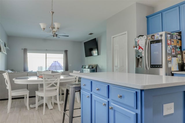 kitchen featuring a kitchen island, decorative light fixtures, ceiling fan, stainless steel refrigerator with ice dispenser, and blue cabinetry