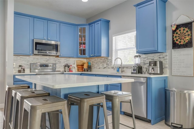 kitchen featuring blue cabinetry, a kitchen bar, sink, a kitchen island, and stainless steel appliances