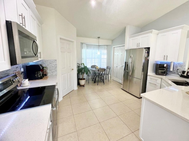 kitchen featuring vaulted ceiling, appliances with stainless steel finishes, light tile patterned flooring, sink, and white cabinets