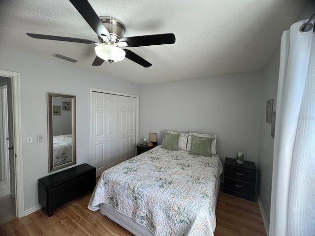 bedroom featuring ceiling fan, hardwood / wood-style floors, a closet, and a textured ceiling