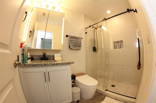 bathroom featuring a shower with door, vanity, hardwood / wood-style flooring, and toilet