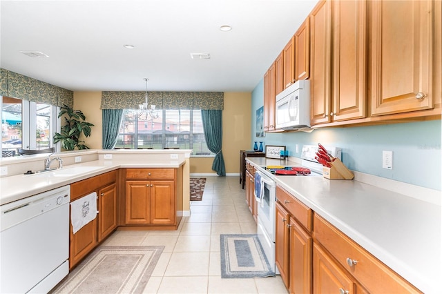 kitchen featuring sink, white appliances, light tile patterned floors, hanging light fixtures, and a notable chandelier