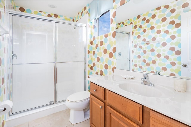 bathroom featuring a shower with door, vanity, tile patterned floors, and toilet