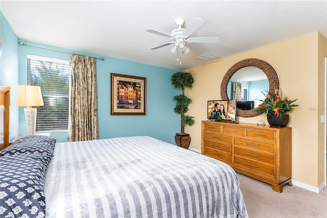 bedroom with ceiling fan, light carpet, and a textured ceiling