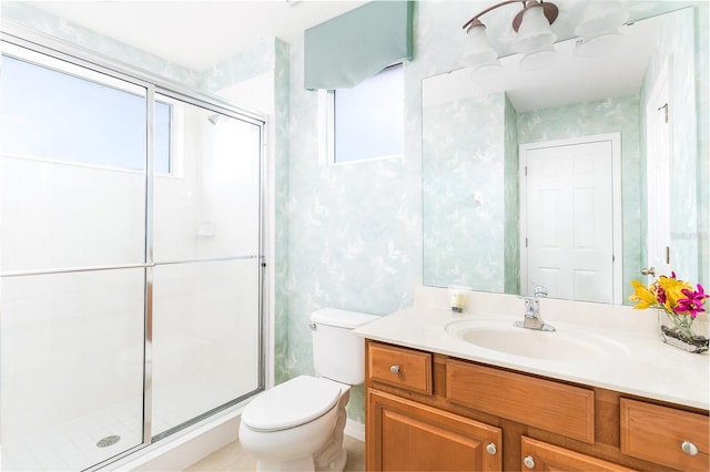 bathroom featuring vanity, a shower with shower door, and toilet