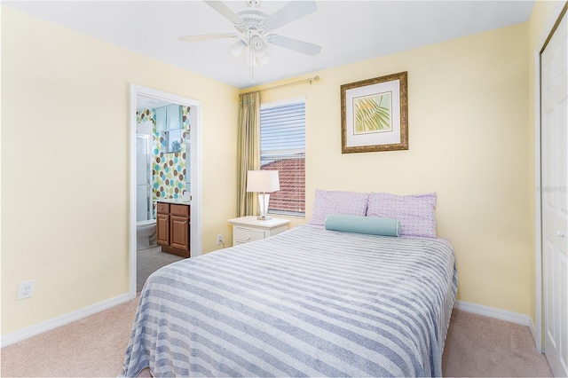 carpeted bedroom featuring ceiling fan, ensuite bath, and a closet