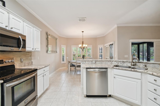 kitchen featuring appliances with stainless steel finishes, sink, white cabinets, light stone counters, and plenty of natural light