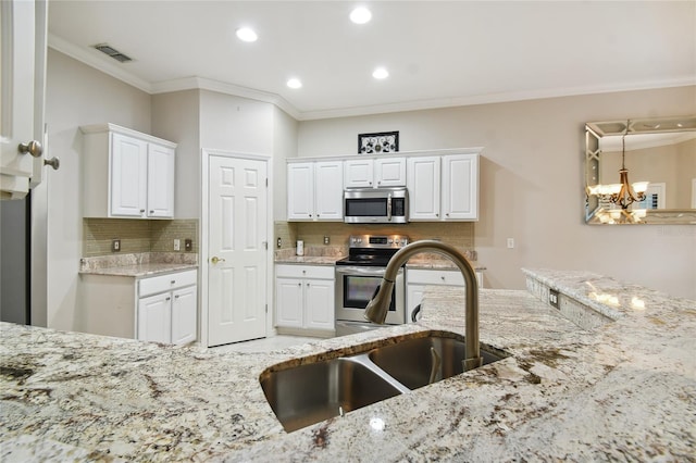 kitchen with stainless steel appliances, sink, white cabinets, and light stone counters