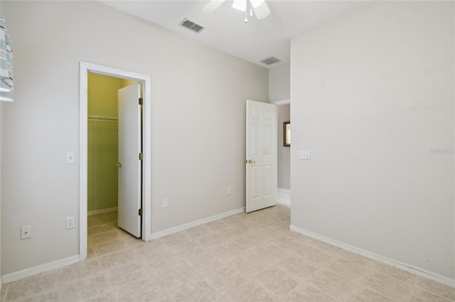 unfurnished bedroom featuring a walk in closet, a closet, ceiling fan, and light tile patterned flooring