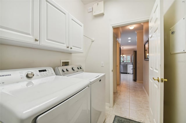 washroom featuring light tile patterned floors, washer and clothes dryer, and cabinets