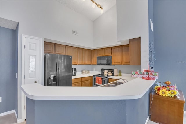 kitchen featuring high vaulted ceiling, kitchen peninsula, sink, and black appliances