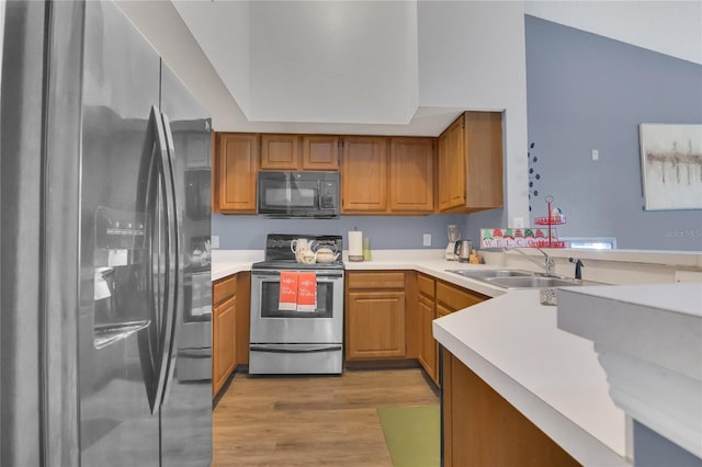 kitchen featuring stainless steel appliances, sink, light wood-type flooring, and kitchen peninsula