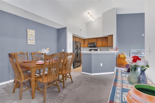 carpeted dining area with high vaulted ceiling