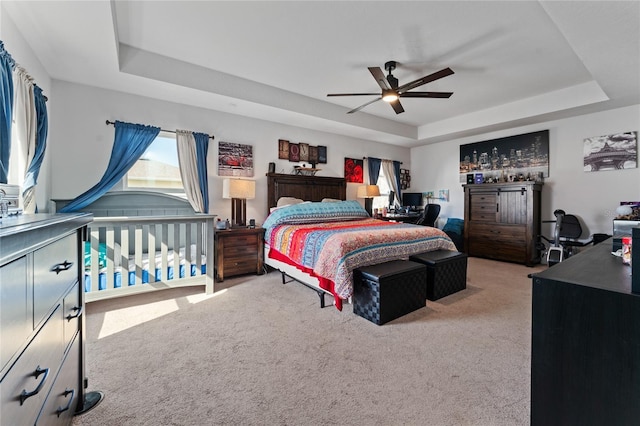 carpeted bedroom with a tray ceiling and ceiling fan